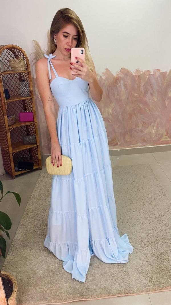 Vestido longo azul claro com alças finas de amarração, busto estruturado e saia fluida em camadas.