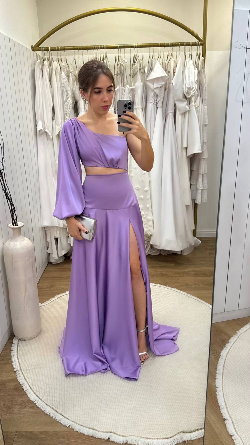 Vestido longo lilás em tecido acetinado, modelo um ombro com manga longa, recorte na cintura e fenda alta na saia.