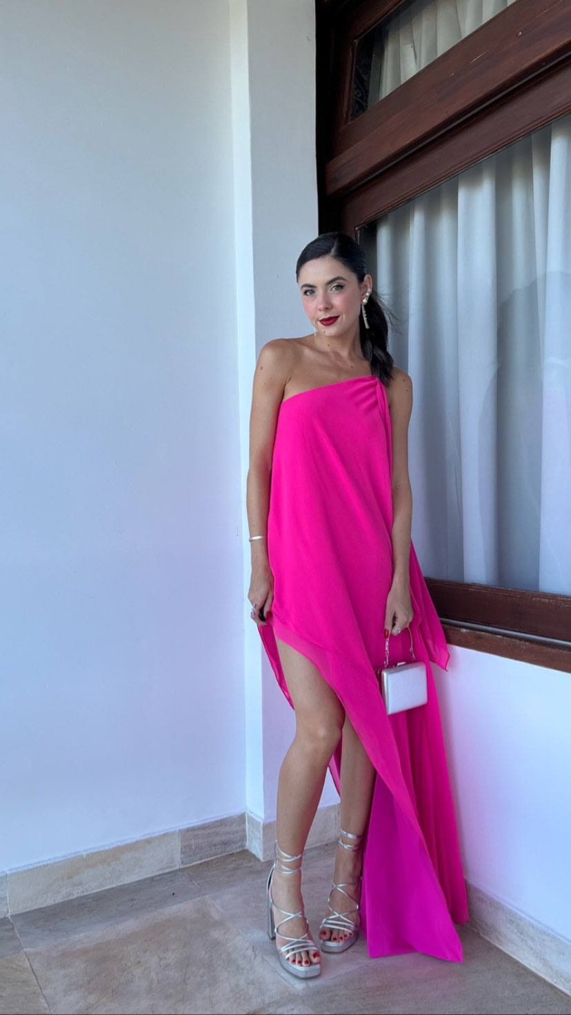 Vestido longo fúcsia em tecido fluido, com decote de um ombro só e fenda alta na saia.