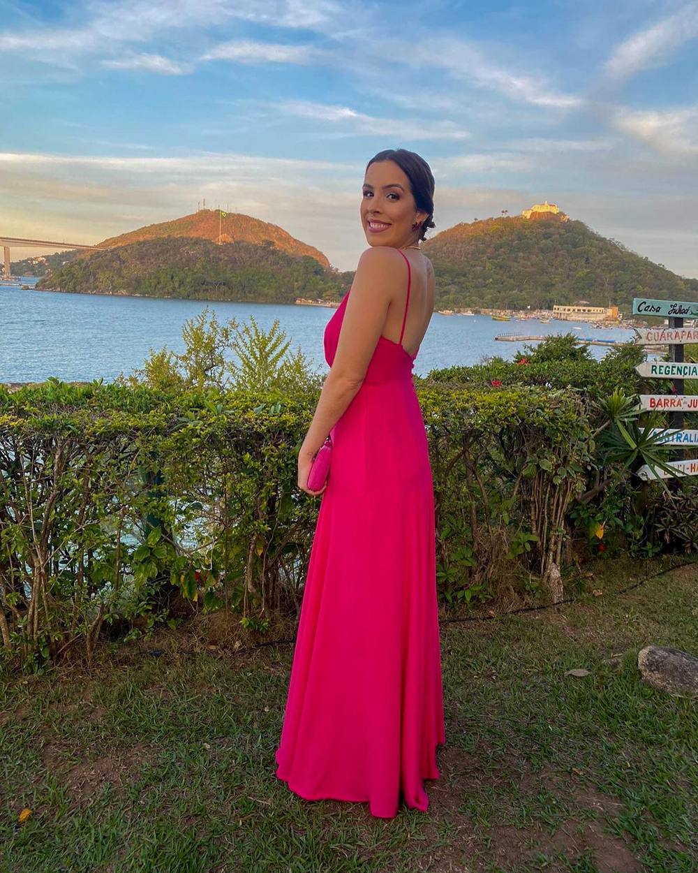 Vestido longo fúcsia de alça fina, com costas abertas e saia fluida e leve.