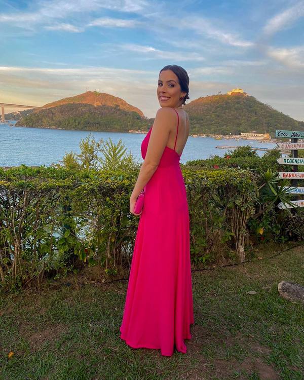 Vestido longo fúcsia de alça fina, com costas abertas e saia fluida e leve.