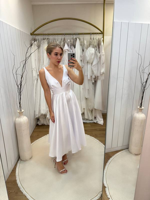 Vestido midi branco em tecido estruturado com decote V profundo, cintura marcada e saia evasê rodada.
