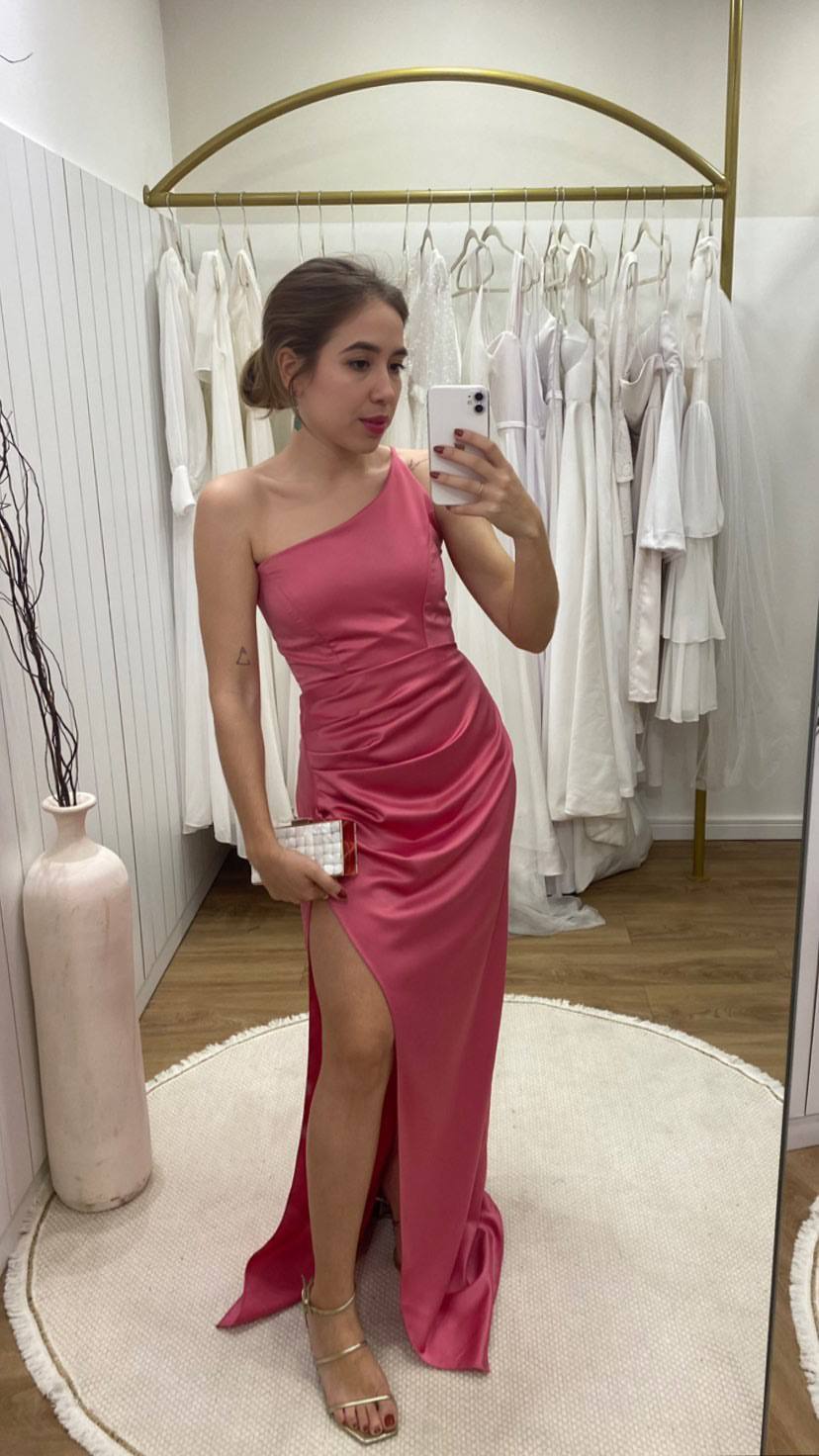 Vestido longo rosa de cetim, com decote de um ombro, drapeado na cintura e fenda profunda.