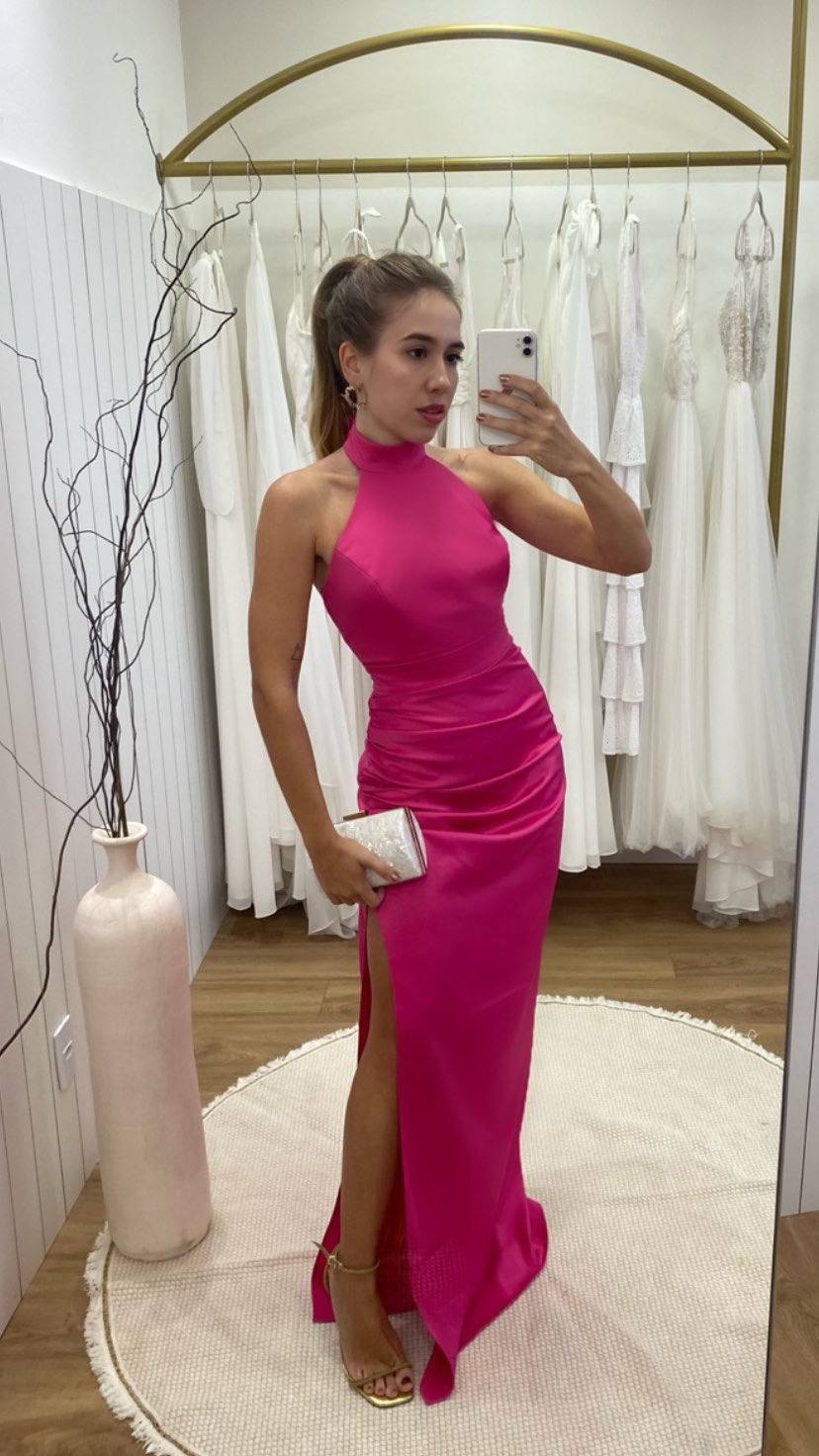Vestido longo fúcsia de gola alta frente única, com drapeado na cintura, caimento reto e fenda lateral.