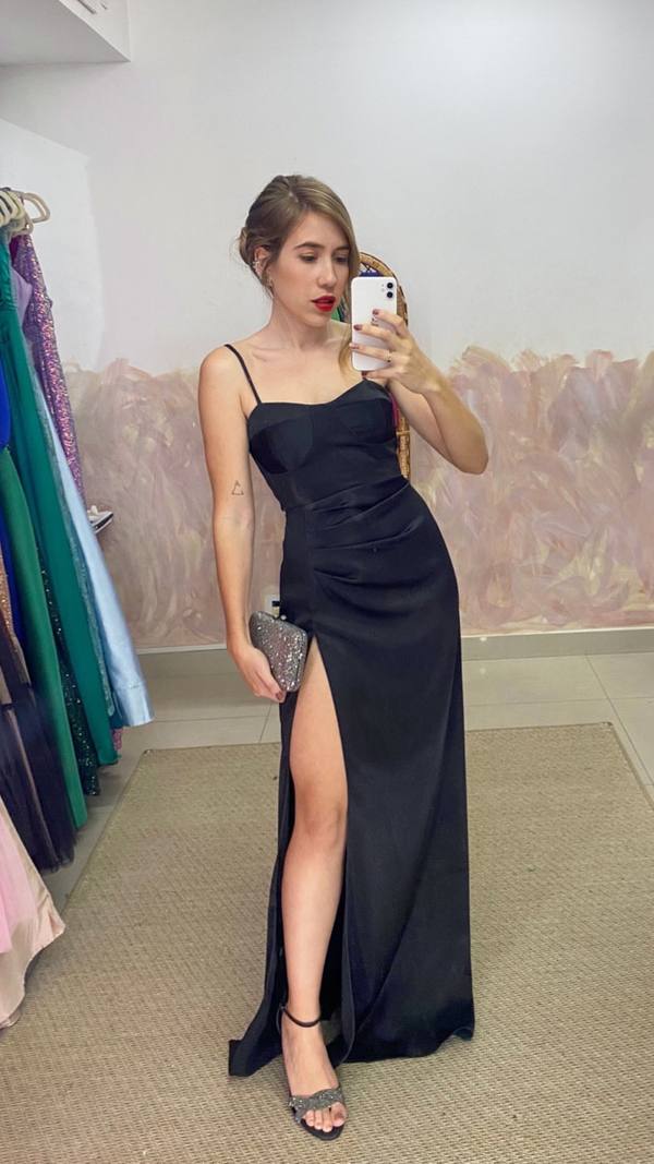 Vestido longo preto de alça fina, com fenda alta lateral e detalhe drapeado na cintura.