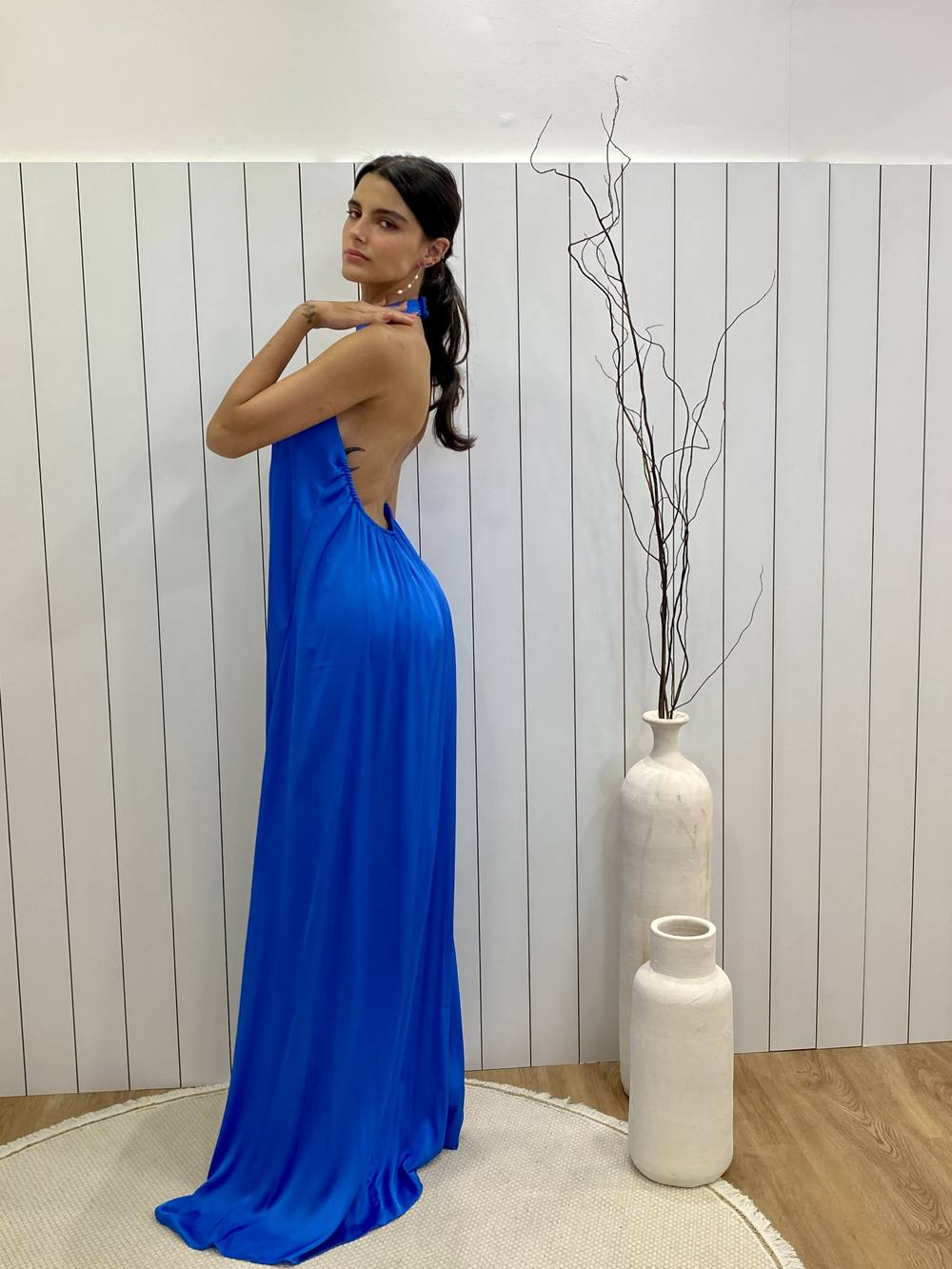 Vestido longo azul de tecido acetinado, estilo frente única, costas nuas e modelagem fluida.