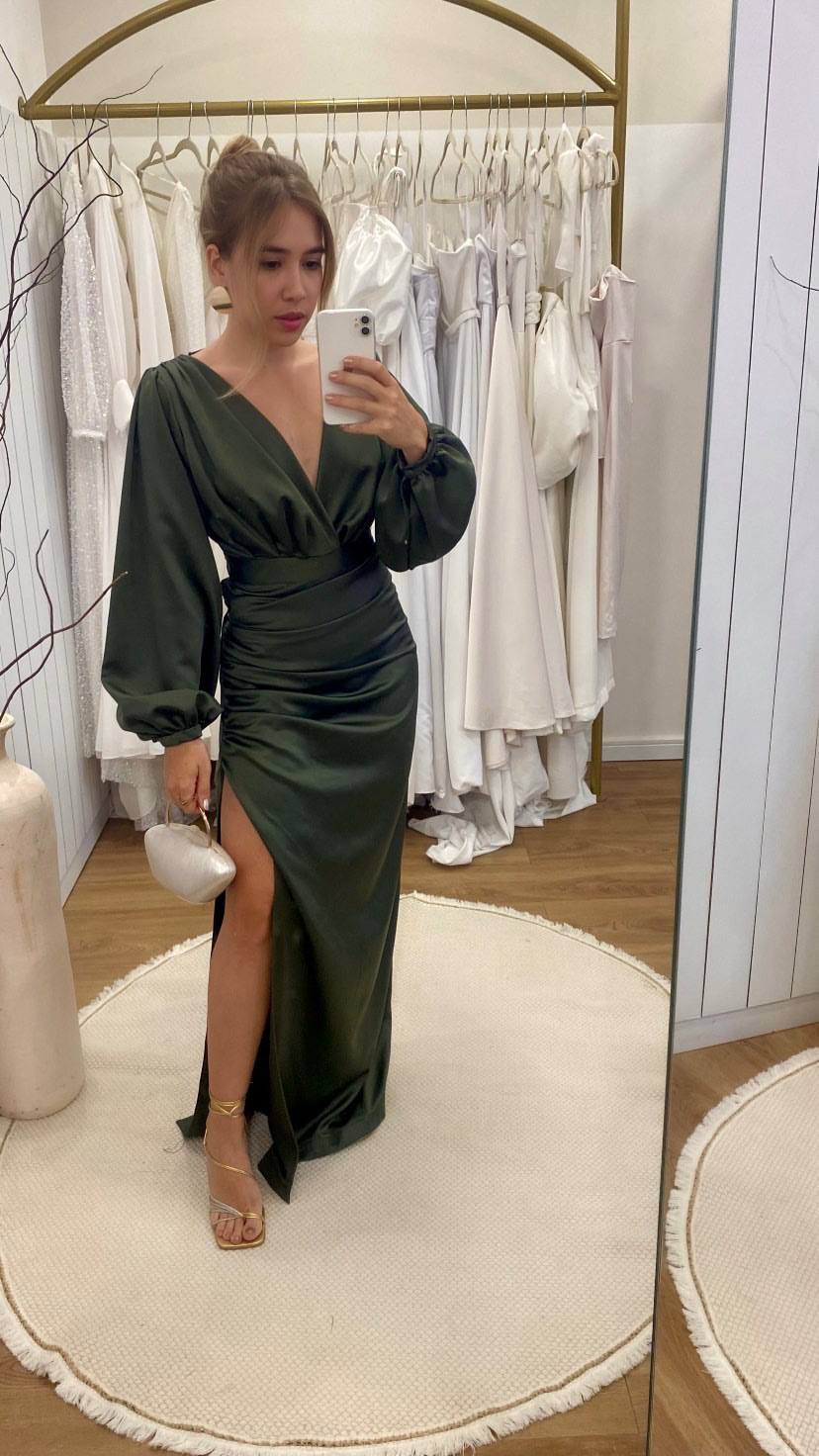 Vestido longo verde oliva em cetim, com mangas longas bufantes, decote V transpassado e fenda na saia.