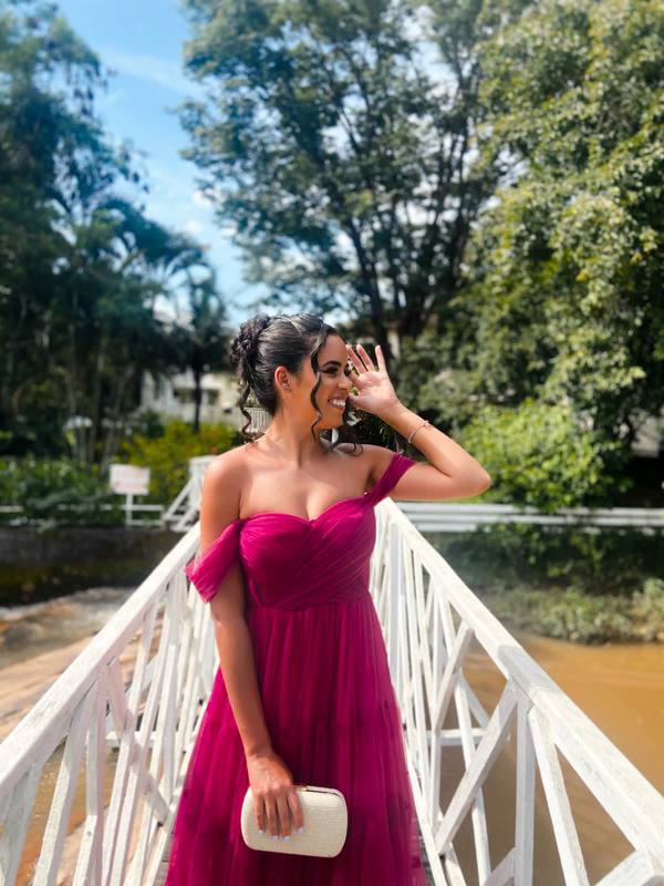 Vestido longo fúcsia em tule, com decote tomara que caia, alças caídas no braço e saia fluida.