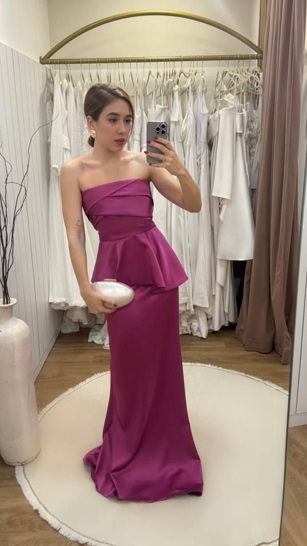 Vestido longo fúcsia tomara que caia em tecido acetinado, com detalhe peplum na cintura e corte reto.