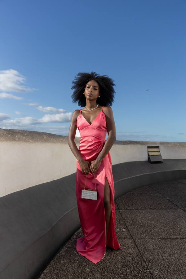 Vestido longo rosa de cetim com alças finas, decote V, fenda lateral profunda e caimento ajustado.