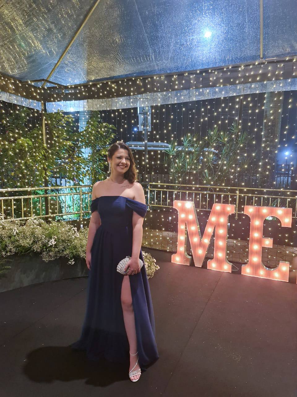 Vestido longo azul escuro fluido, com decote tomara que caia, mangas ombro a ombro e fenda lateral na saia.