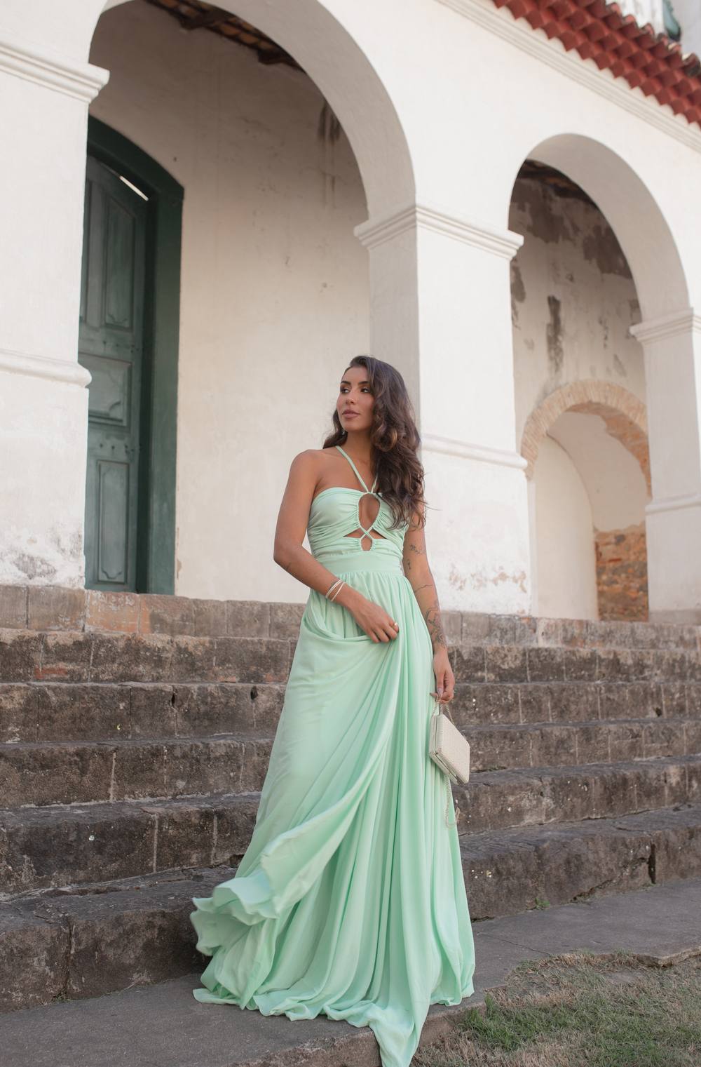 Vestido longo verde claro em tecido fluido, decote frente única com recortes no busto e saia esvoaçante.