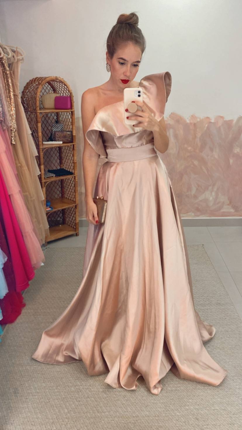 Vestido longo rosé de cetim, com decote um ombro com babado estruturado e saia ampla evasê.